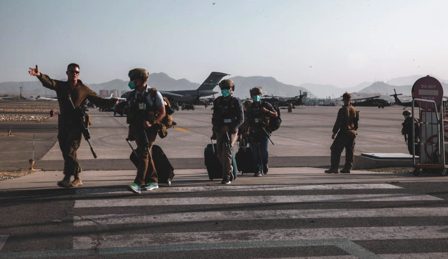 A U.S. Marine assigned to the 24th Marine Expeditionary Unit escorts Department of State personnel to be processed for evacuation at Hamid Karzai International Airport, Kabul, Afghanistan, August 15, 2021. (US Navy/Central Command Public Affairs/Sergeant Isaiah Campbell/Handout via Reuters)